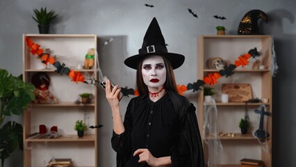 Vampire witch with a smartphone in a Halloween setting