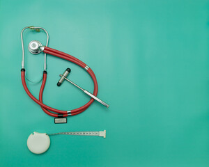 red stethoscope, medical hammer and measuring tape on green Background, Space for Text, Space for...