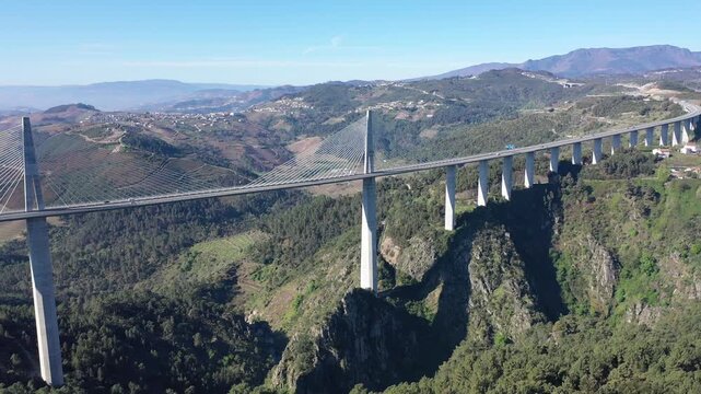 Drone view of picturesque spring landscape with mountains covered with green forests in Vila Real district in Portugal and high modern suspension viaduct with highway crossing Corgo River gorge