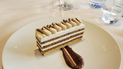 This elegant layered dessert with cream, sponge cake, and chocolate garnish is served at a restaurant in Paris.
