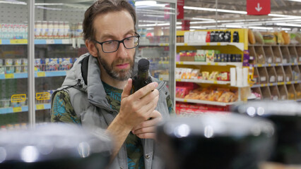 A male customer examining a glass bottle of oil in a shopping mall