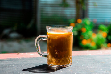 Iced Coffee in Ribbed Glass Jar on Weathered Table with Garden Background