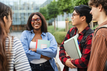 African American female student together with group classmates meeting in front of the university building, talking about school project 