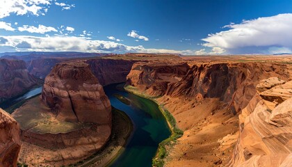 Fototapeta premium A breathtaking panoramic view of a horseshoe bend carved by a river through sandstone cliffs.