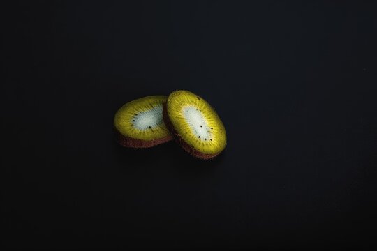 Two kiwi slices on dark background