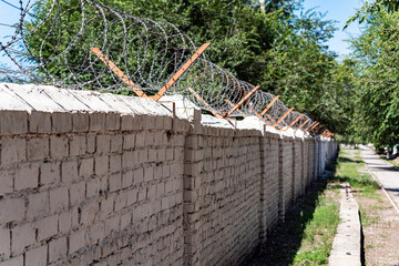 The fence is made of white brick, on top of which there is a Razor wire  to provide enhanced...