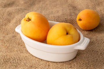 Organic ripe apricots on jute cloth, macro.
