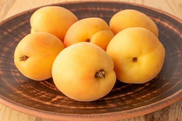 Organic ripe apricots on a clay plate, close-up.