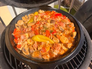 Beef meat and vegetables stew in black bowl with roasted baby potatoes. Dark background grill kamado bbq.