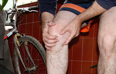Hombre con artrósis sujetándose con las manos su rodilla lesionada e inflamada con molestias y...