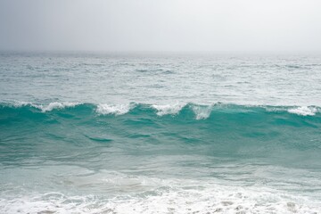 Serene ocean wave under overcast sky.