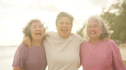 Happy Asian senior woman friends walking together on the beach at sunset. Group of Healthy wellness elderly people enjoy and fun outdoor lifestyle travel nature the sea on summer holiday vacation. - Powered by Adobe