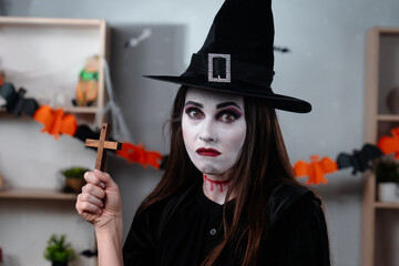 Halloween vampire witch with a cross in a spooky room