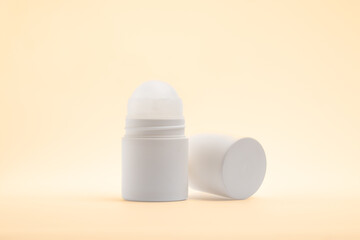 a white roll-on deodorant bottle with its cap placed next to it on a light, 