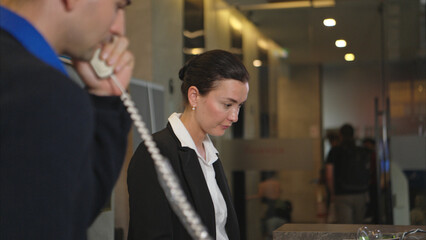 A hotel receptionist assisting with check-in and check-out, smiling and eager