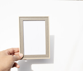 Close-up of a man’s hands holding an empty wooden frame on a clean white background, ready for...