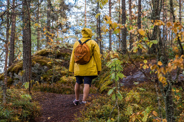 Tourism. Hiking. Ladoga skerries on Lake Ladoga. A male tourist in a yellow raincoat with a...