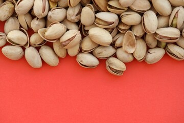 Tasty unpeeled pistachios on bright red background, top view flat lay background pattern