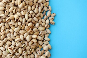 Tasty unpeeled pistachios on bright blue background, top view flat lay background pattern