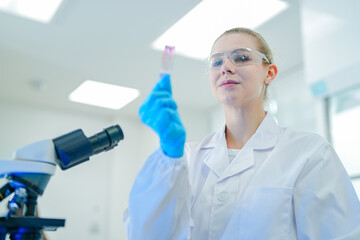 A confident female histologist inspects a stained tissue slide after processing, checking the...