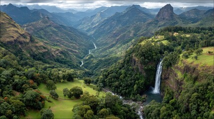Majestic mountain valley showcasing a stunning waterfall cascading down a sheer cliff face, surrounded by lush greenery and rolling hills.