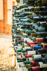 Obraz premium Colorful wine bottle necks embedded in a brick wall, captured in Mtskheta, Georgia. Creative recycled structure representing local winemaking heritage and design