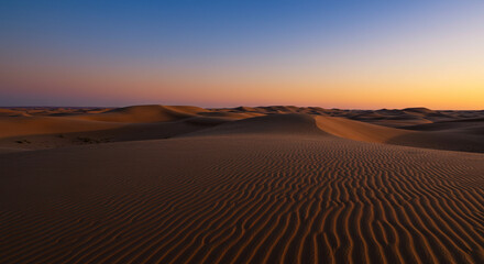A scenic desert landscape with rolling sand dunes under a vibrant sunset sky at golden hour light