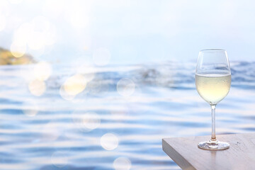 a glass of white wine, a background under the summer sun, a bokeh and sun glare, a blurred abstract background