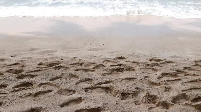 Footprints on sandy beach near ocean waves in Angso Duo Island, Pariaman, Indonesia