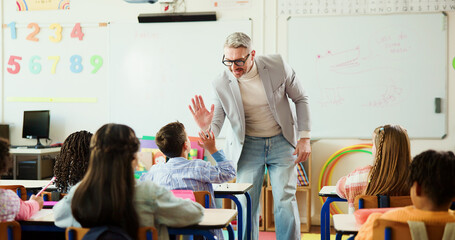 Teacher, boy and high five for learning in classroom with smile, support and education at school....