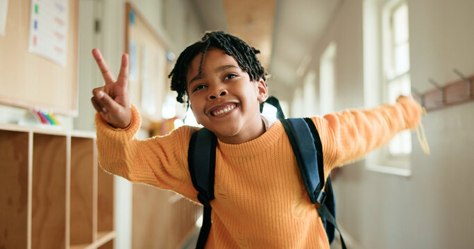 Education, peace sign and smile of black child in school corridor for development, learning or study. Emoji, future and growth with happy African boy in academy hallway for knowledge as student
