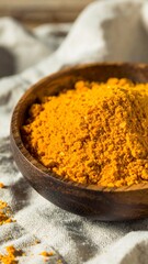 Pile of bright yellow spice in a wooden bowl