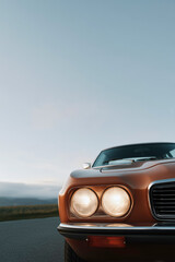 Fototapeta premium Vintage classic car front view with headlights on under clear sky retro automobile design