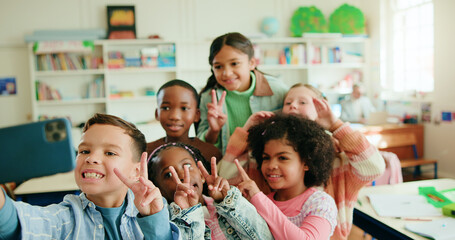 Education, peace sign and selfie with children in class together for learning or memories. Development, growth and profile picture with group of happy kids in school classroom for social media