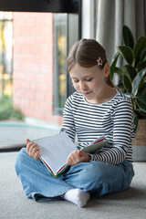 Cute girl reading book at home by window in cozy setting