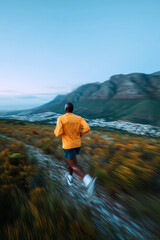 Obraz premium Runner in orange jacket jogging through scenic mountain valley outdoor fitness lifestyle