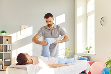Therapist provides a leg and joint massage to a patient during a rehabilitation and physiotherapy session in a clinic. Physical knee stretching and the therapeutic process in patient care.