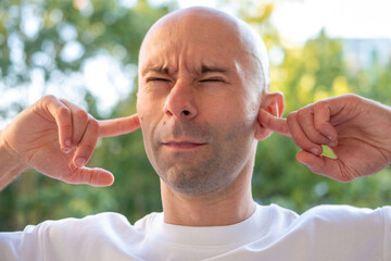 bald man hearing or listening deeply, ear with pained expression, discomfort loud noise, hearing...
