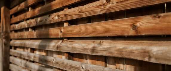 Close-up of a rustic wooden fence with horizontal planks, showing rich texture and sunlight.
