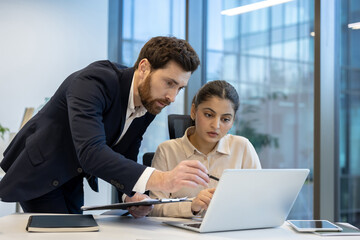 Business colleagues collaborating on laptop in modern office