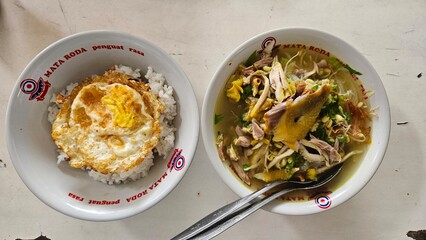 A plate of rice and fried egg with a plate of chicken soto