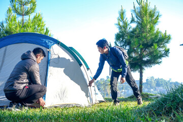 Two Men Work Together To Prepare Tent In Grassy