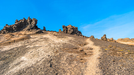 Panoramic view at Askja caldera hiking trail in the lifeless volcanic desert in Highlands, with stones and rocks thrown by volcanic eruptions, Iceland, summer, blue sky.