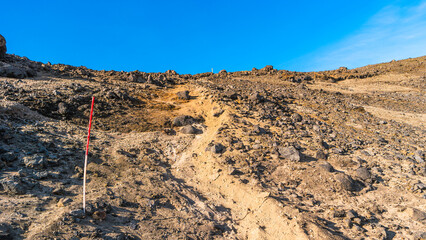 Panoramic view at Askja caldera hiking trail in the lifeless volcanic desert in Highlands, with stones and rocks thrown by volcanic eruptions, Iceland, summer, blue sky.