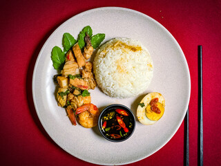 Stir-fried seafood with holy basil served over rice, a spicy and aromatic Thai street food dish packed with shrimp, squid, and fish.