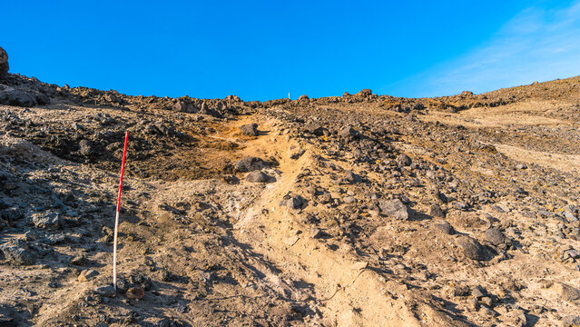 Panoramic view at Askja caldera hiking trail in the lifeless volcanic desert in Highlands, with stones and rocks thrown by volcanic eruptions, Iceland, summer, blue sky.