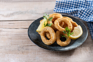 Crispy fried squid rings on wooden table. Copy space