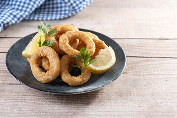 Crispy fried squid rings on wooden table. Copy space