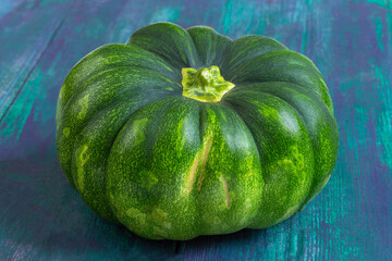 Fresh green pumpkin on a colorful surface