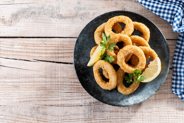 Crispy fried squid rings on wooden table. Top view. Copy space